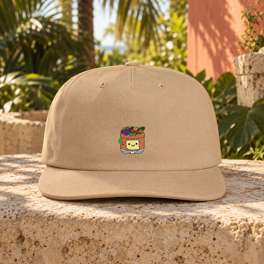 Khaki Pothead Cap with a colorful smiling flowerpot character, shown on a stone ledge.