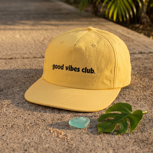 Yellow Sunrise Surf Cap with a black good vibes club. wordmark, shown outdoors.
